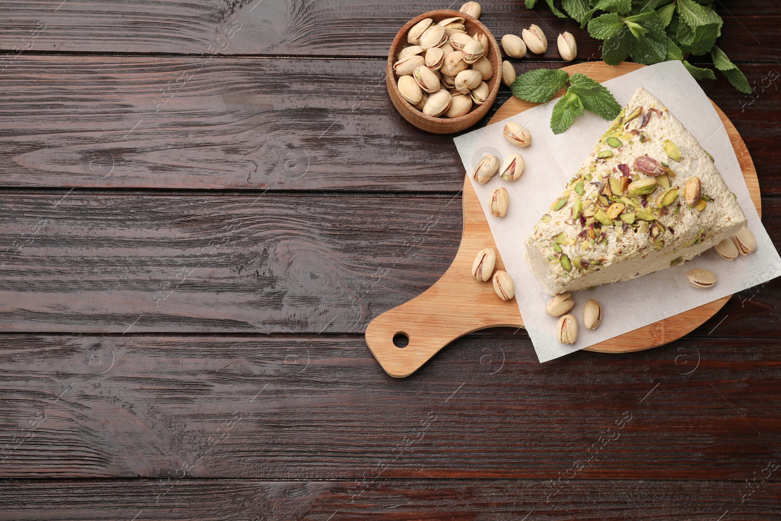 Photo of Piece of tasty halva with pistachios and mint on wooden table, flat lay. Space for text