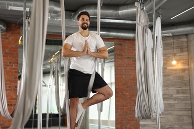 Photo of Young man practicing fly yoga on hammock in studio