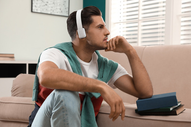 Man listening to audiobook near sofa at home