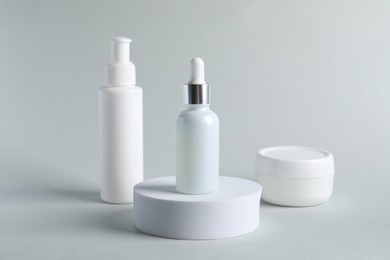 Bottles with cosmetic serums on light grey background