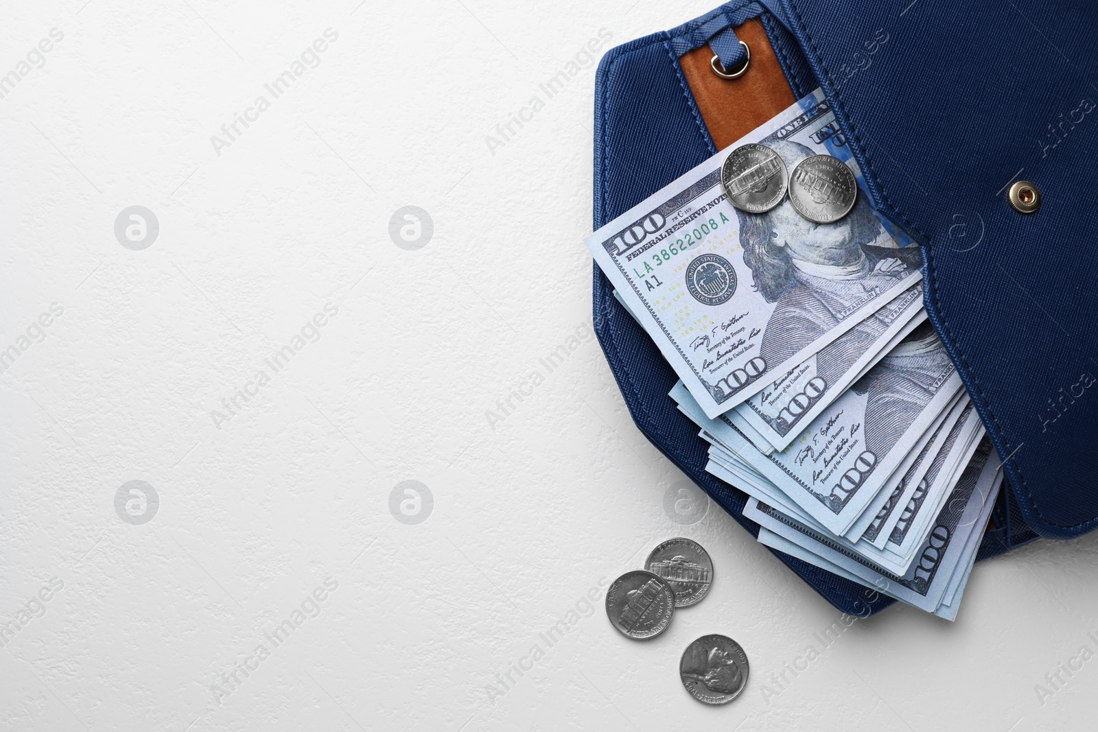 Photo of Dollar banknotes in wallet and coins on white table, flat lay with space for text. Money exchange