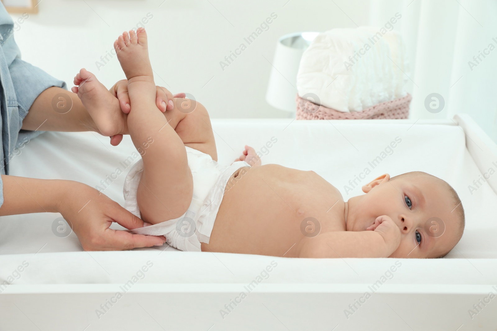 Photo of Mother changing her baby's diaper on table at home