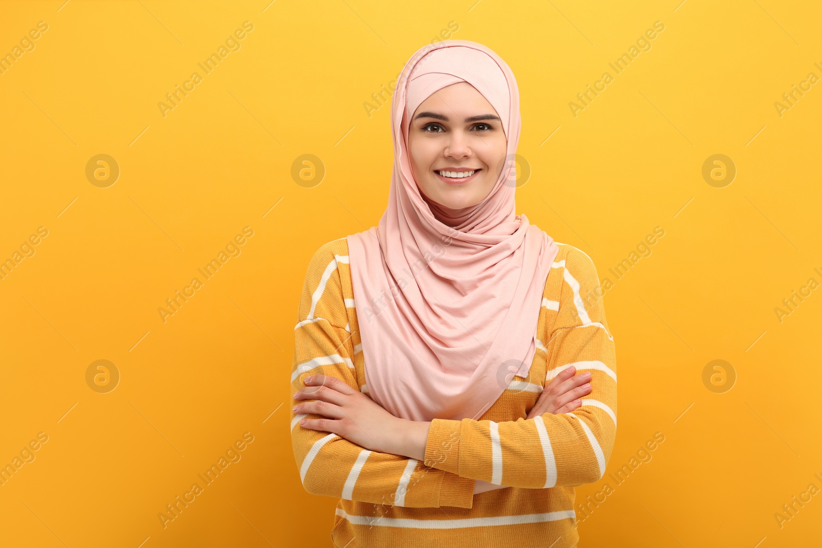 Photo of Portrait of Muslim woman in hijab on orange background