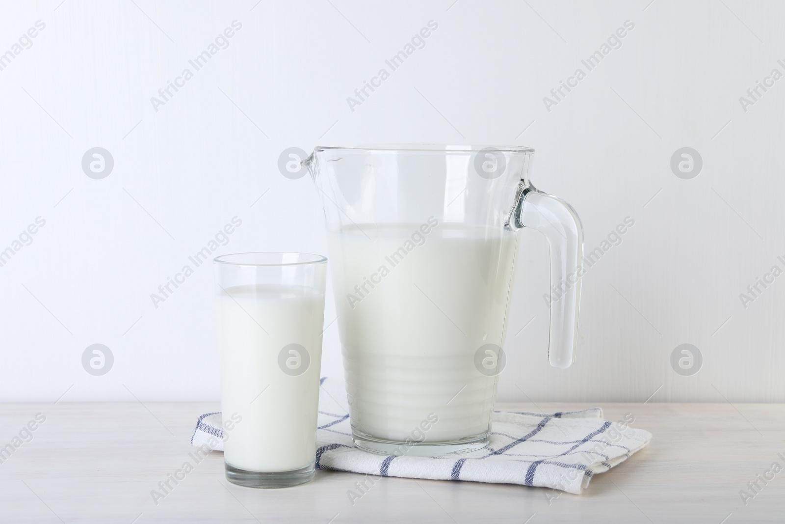 Photo of Jug and glass of fresh milk on wooden table