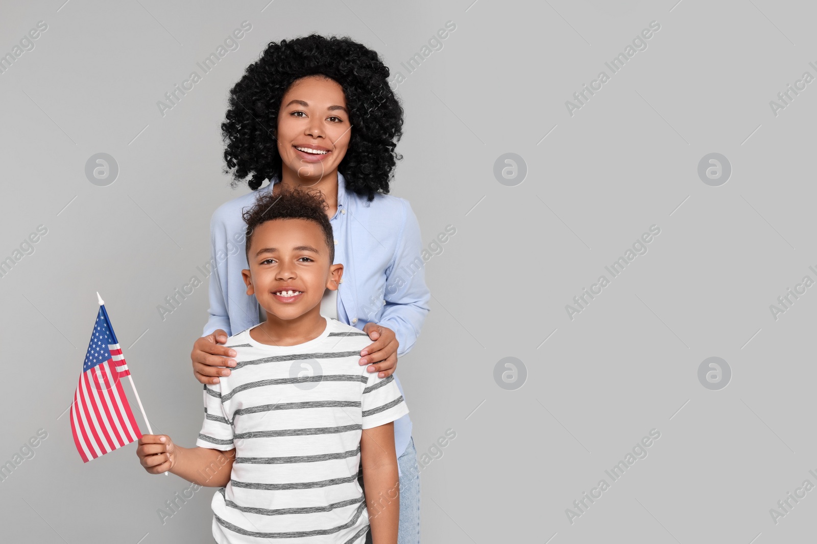 Photo of 4th of July - Independence Day of USA. Happy woman and her son with American flag on light grey background, space for text