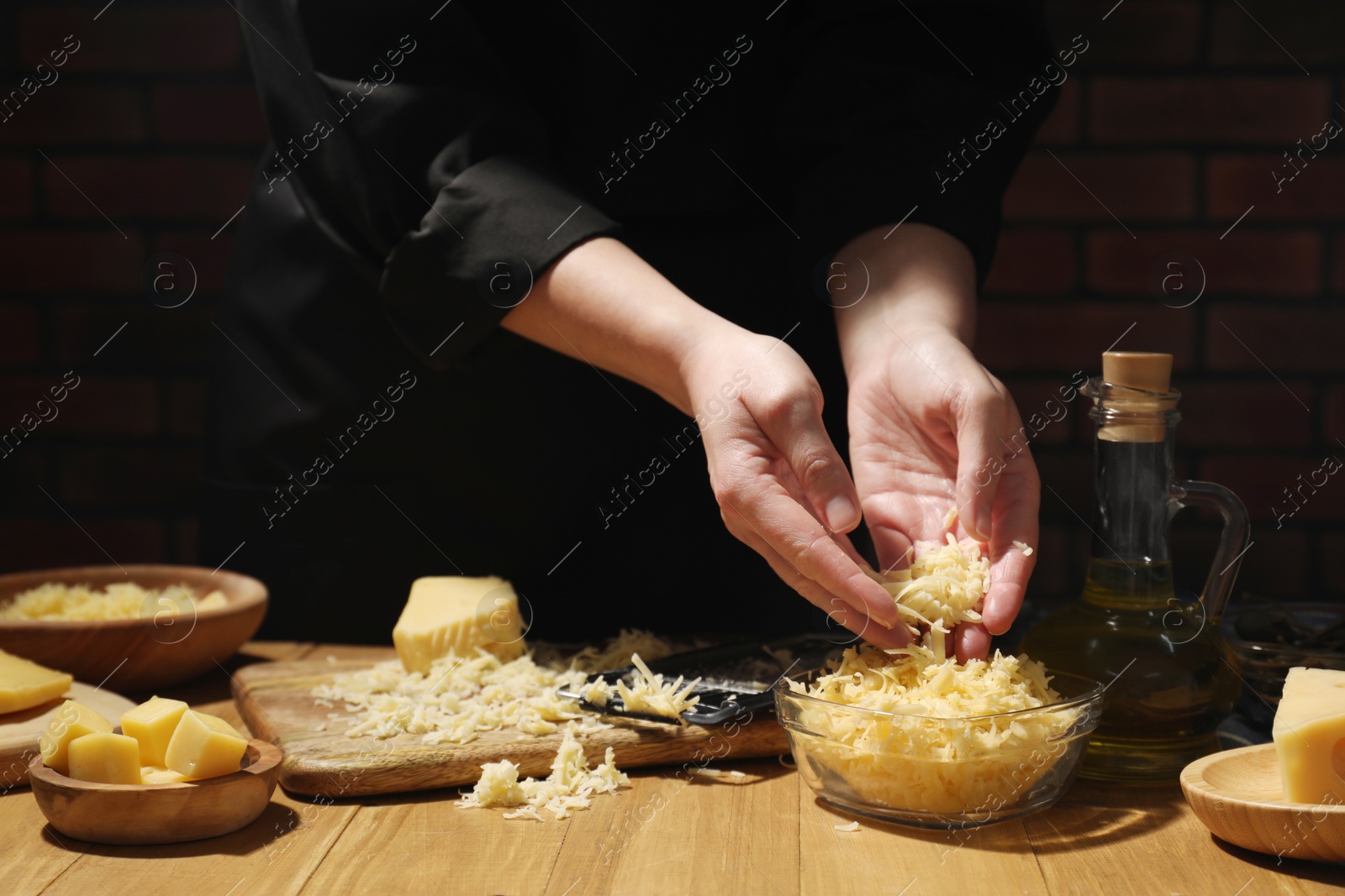 Photo of Woman with grated cheese at wooden table, closeup