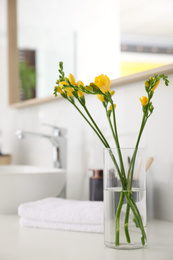 Beautiful yellow freesia flowers on countertop in bathroom