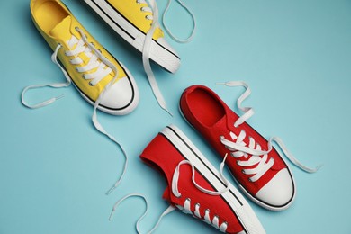 Photo of Red and yellow classic old school sneakers on light blue background, flat lay