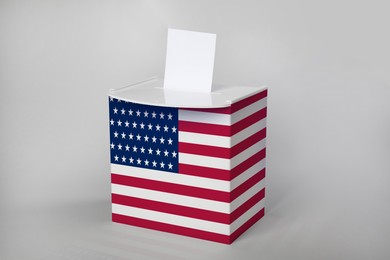 Ballot box decorated with flag of USA on light background