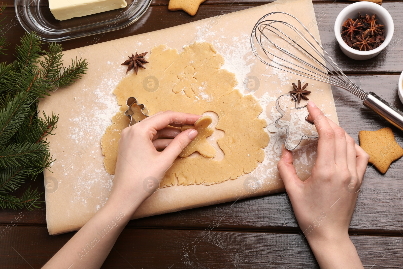 Photo of Woman making Christmas cookies with cutters at wooden table, top view