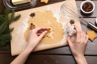 Woman making Christmas cookies with cutters at wooden table, top view