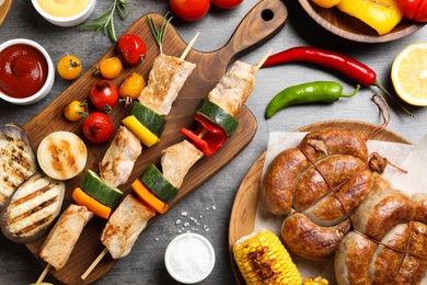 Photo of Flat lay composition with barbecued meat and vegetables on grey table