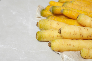 Photo of Raw white and yellow carrots on light grey marble table, closeup