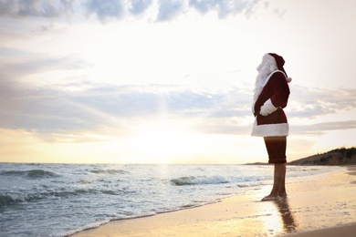 Photo of Santa Claus on beach, space for text. Christmas vacation