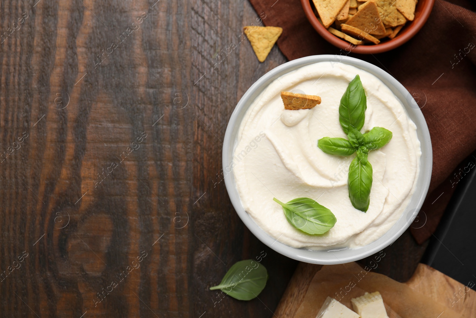 Photo of Delicious tofu sauce served with crunchy snack on wooden table, flat lay. Space for text