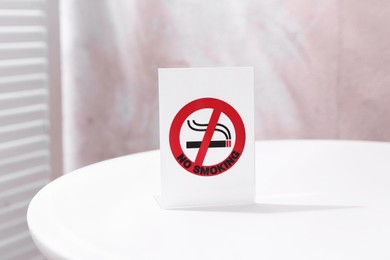 Photo of No Smoking sign on white table indoors