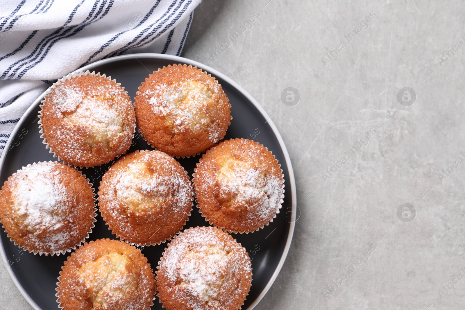 Photo of Delicious sweet muffins on light grey textured table, top view. Space for text