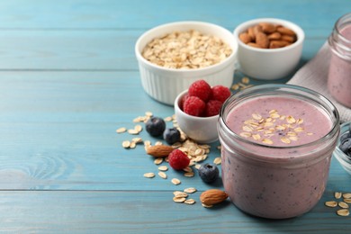 Photo of Tasty berry smoothie with oatmeal on light blue wooden table. Space for text