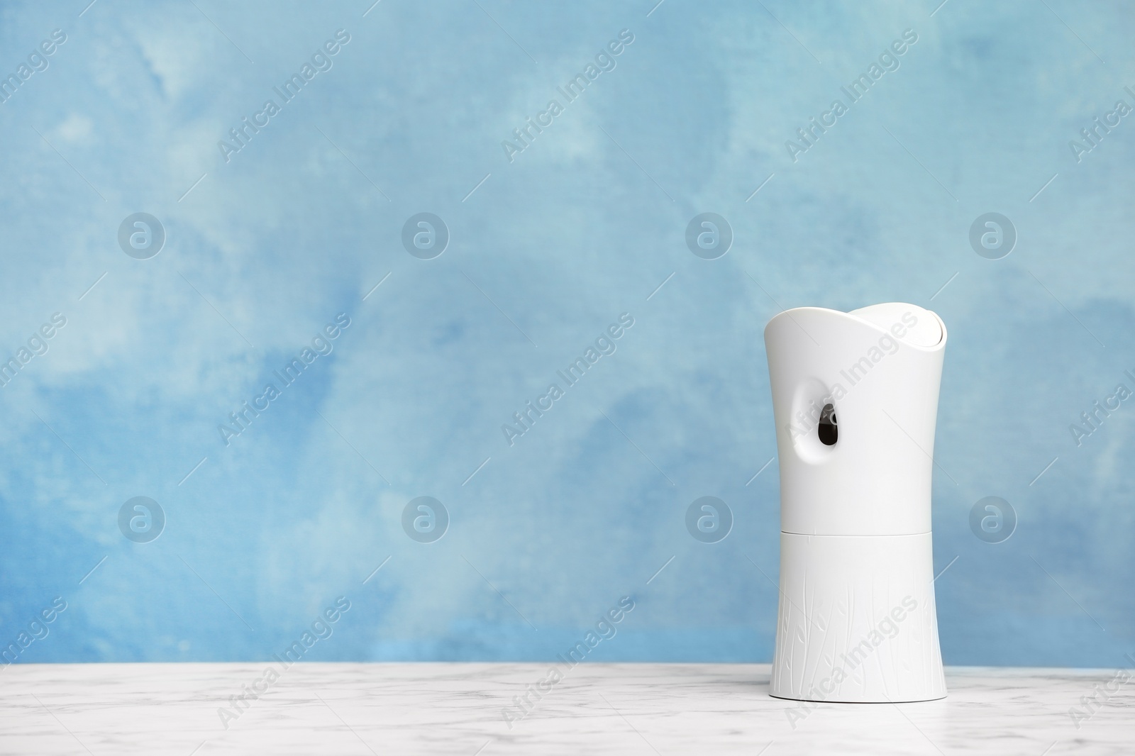 Photo of Automatic air freshener on table against color background