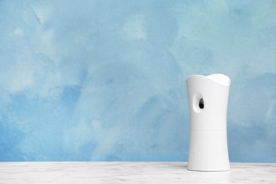 Photo of Automatic air freshener on table against color background