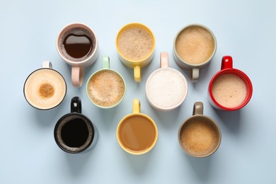 Photo of Many different cups with aromatic coffee on light blue table, flat lay