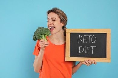 Photo of Woman holding blackboard with phrase Keto Diet and broccoli on light blue background