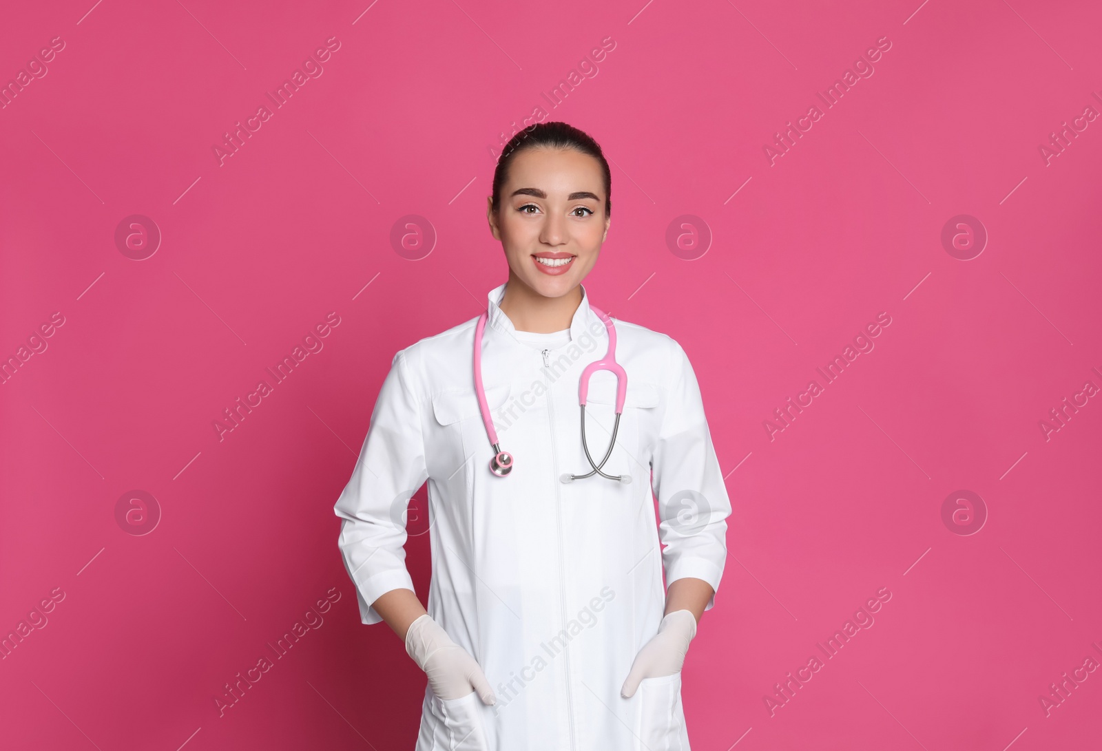 Photo of Portrait of beautiful young doctor on pink background