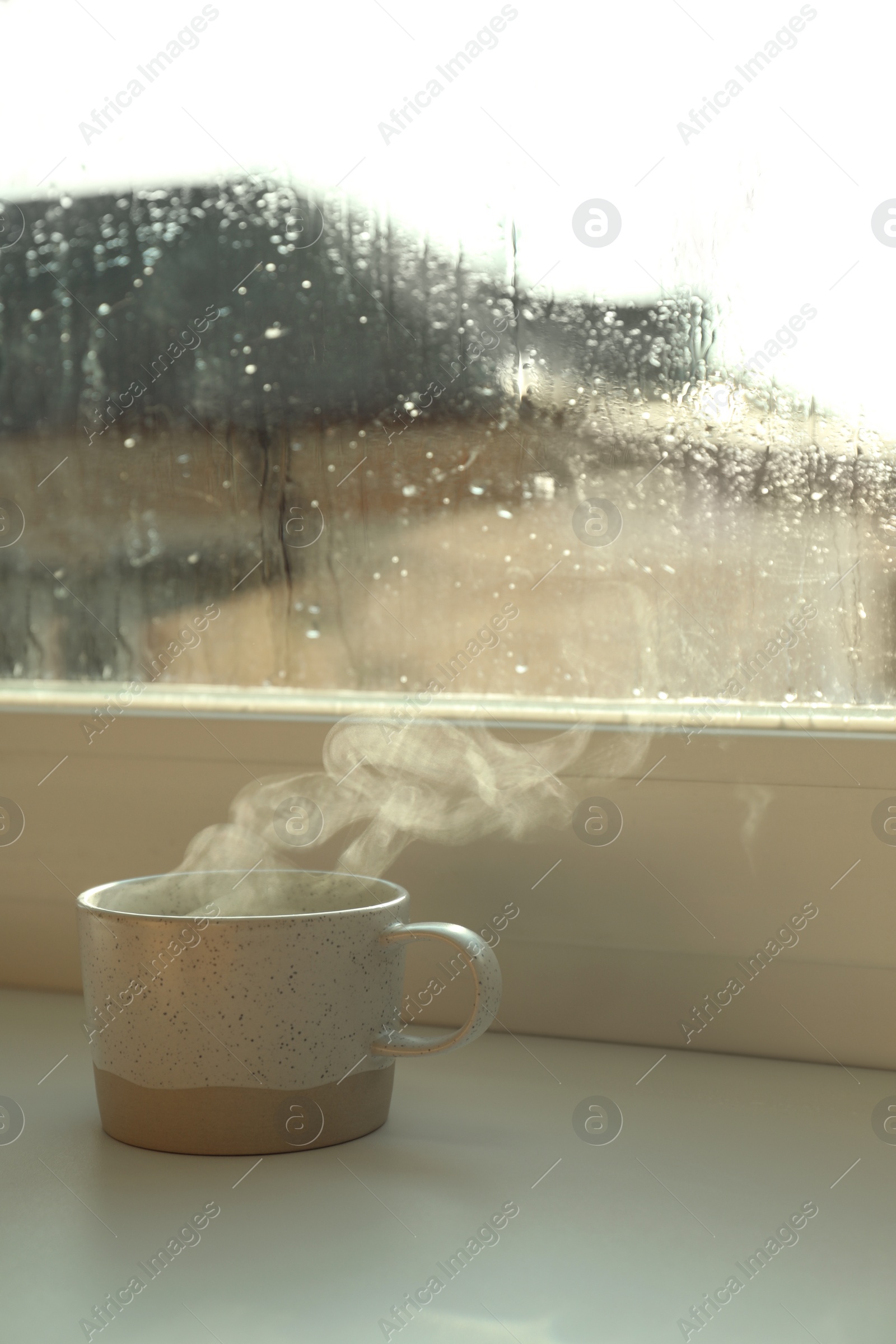 Photo of Cup of hot drink near window on rainy day. Space for text