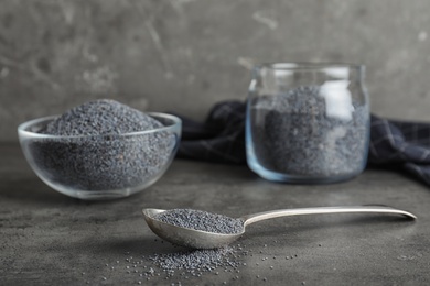 Photo of Poppy seeds in spoon and other dishware on table