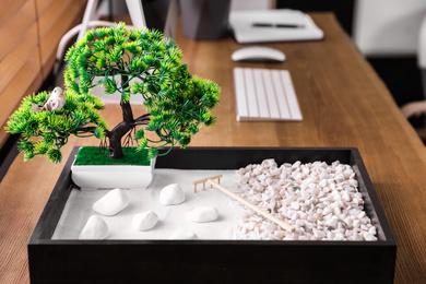 Photo of Beautiful miniature zen garden and computer on wooden table in office