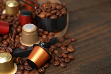 Coffee capsules and beans on wooden table, closeup. Space for text