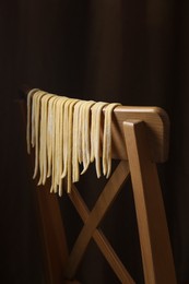 Homemade pasta drying on chair against dark background