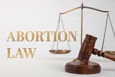 Abortion Law. Gavel and scales of justice on table against white background