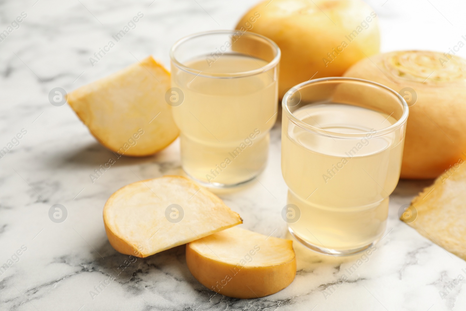 Photo of Glasses of freshly made turnip juice on white marble table