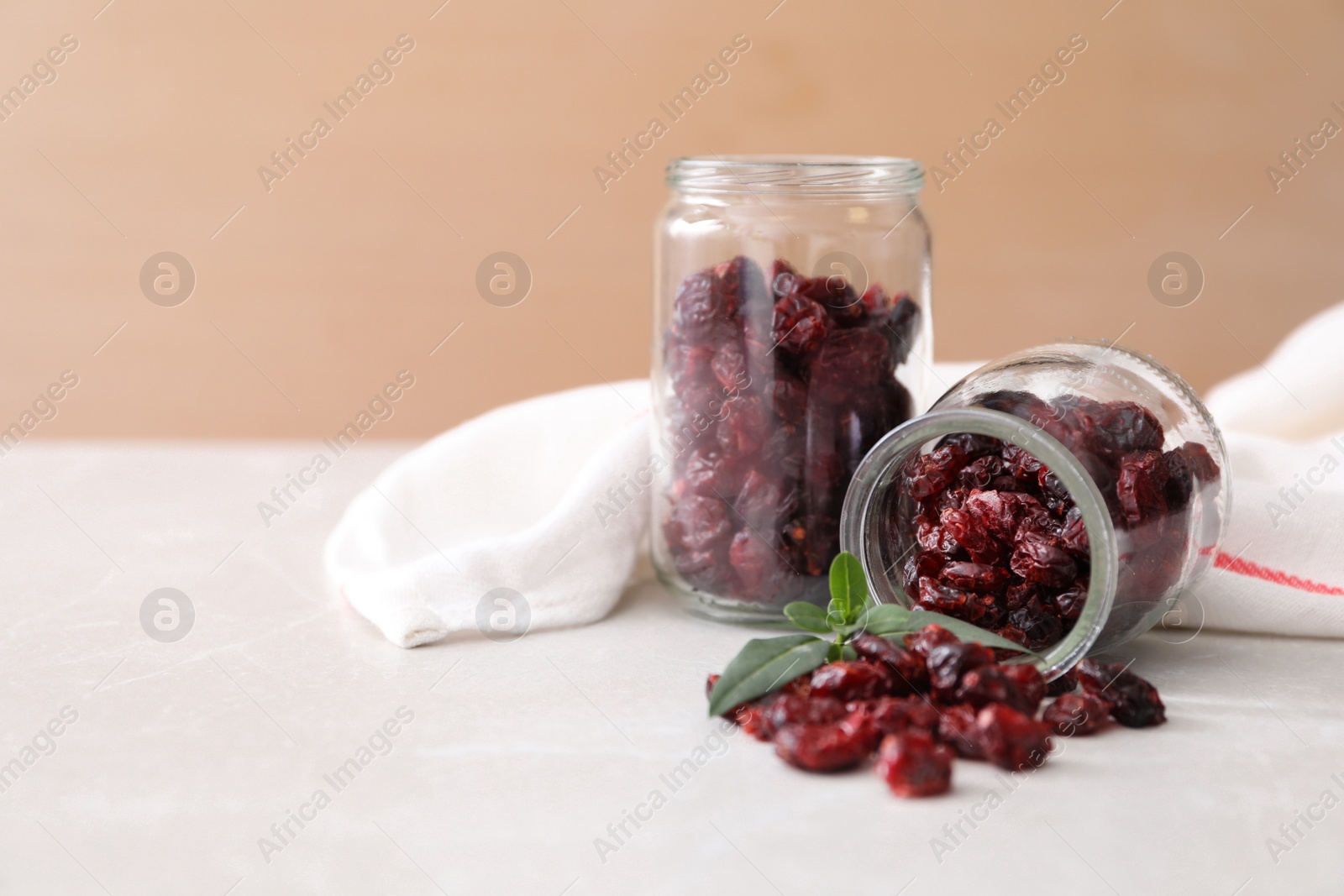 Photo of Jars with dried cranberries on light table, space for text