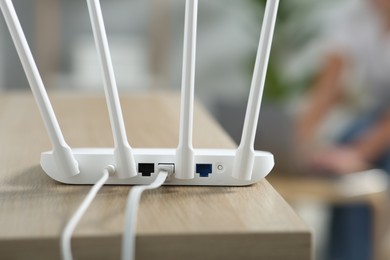 Photo of New modern Wi-Fi router on wooden table indoors, closeup