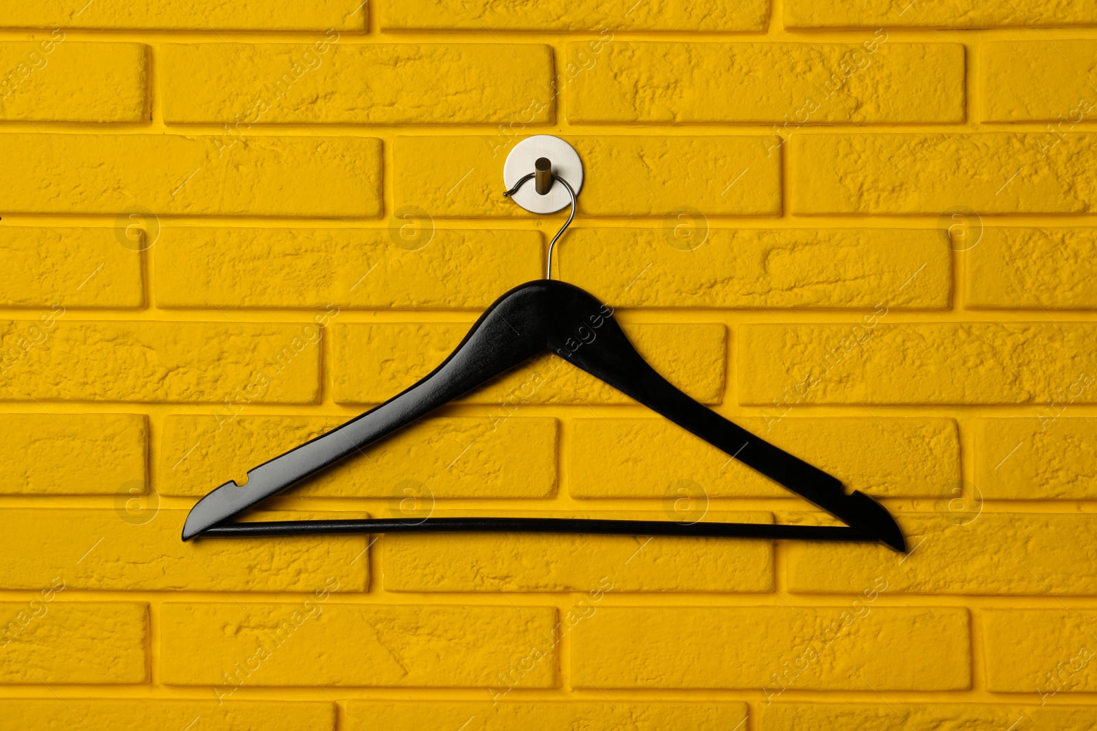 Photo of Empty clothes hanger on yellow brick wall