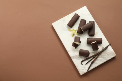 Photo of Glazed curd cheese bars, vanilla pods and flower on light brown background, top view. Space for text