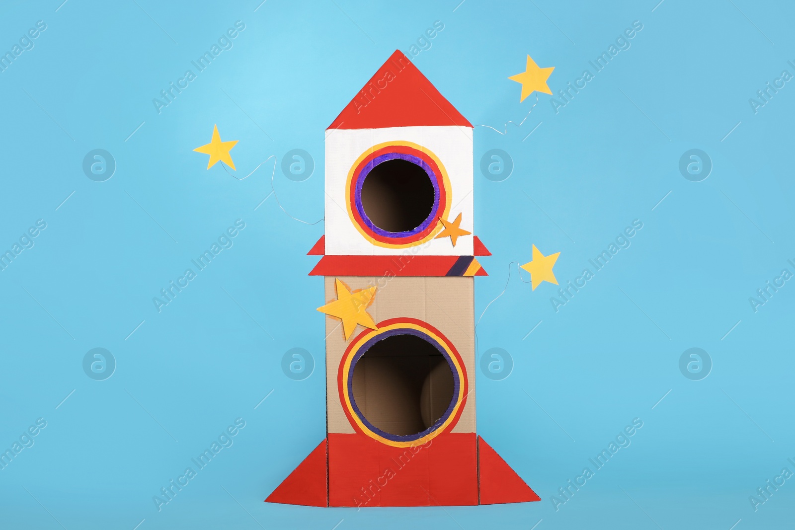 Photo of Cute handmade cardboard spaceship on light blue background