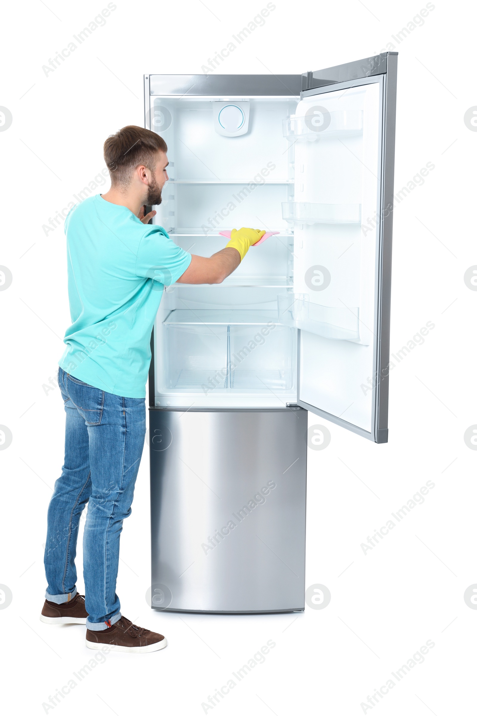 Photo of Young man cleaning refrigerator with rag on white background