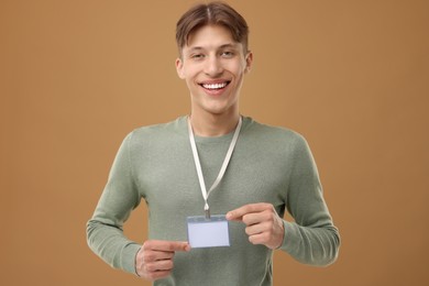 Happy man with blank badge on light brown background