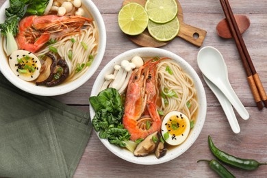 Delicious ramen with shrimps in bowls served on wooden table, flat lay. Noodle soup