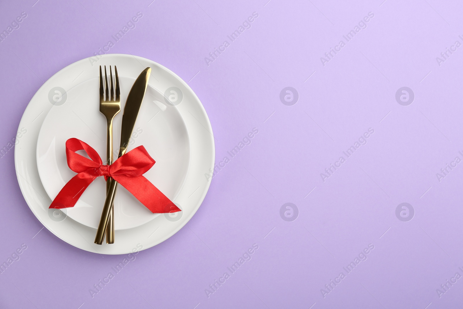 Photo of Beautiful table setting on violet background, top view with space for text. Valentine's Day dinner