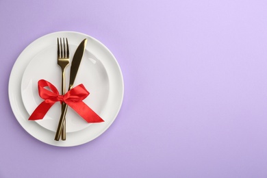 Photo of Beautiful table setting on violet background, top view with space for text. Valentine's Day dinner