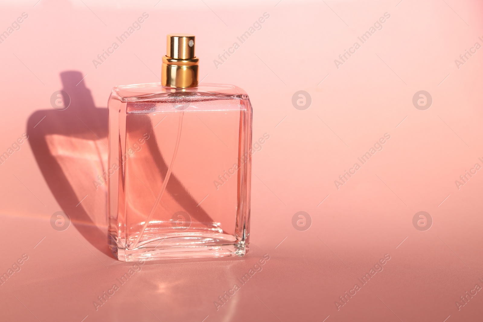 Photo of Luxury women's perfume in bottle on pink background. Space for text