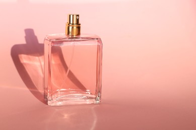 Photo of Luxury women's perfume in bottle on pink background. Space for text