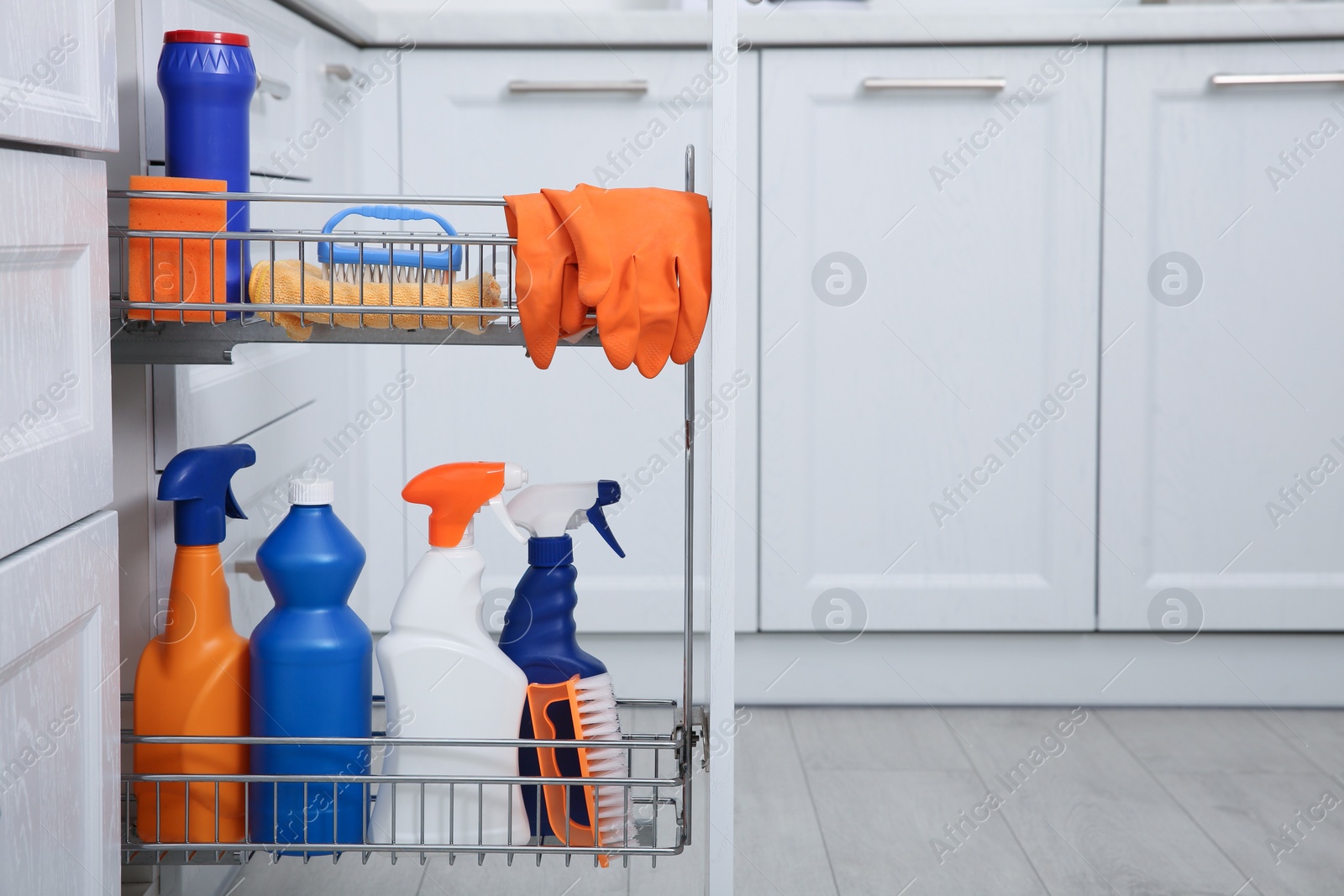 Photo of Open drawer with different cleaning supplies in kitchen. Space for text