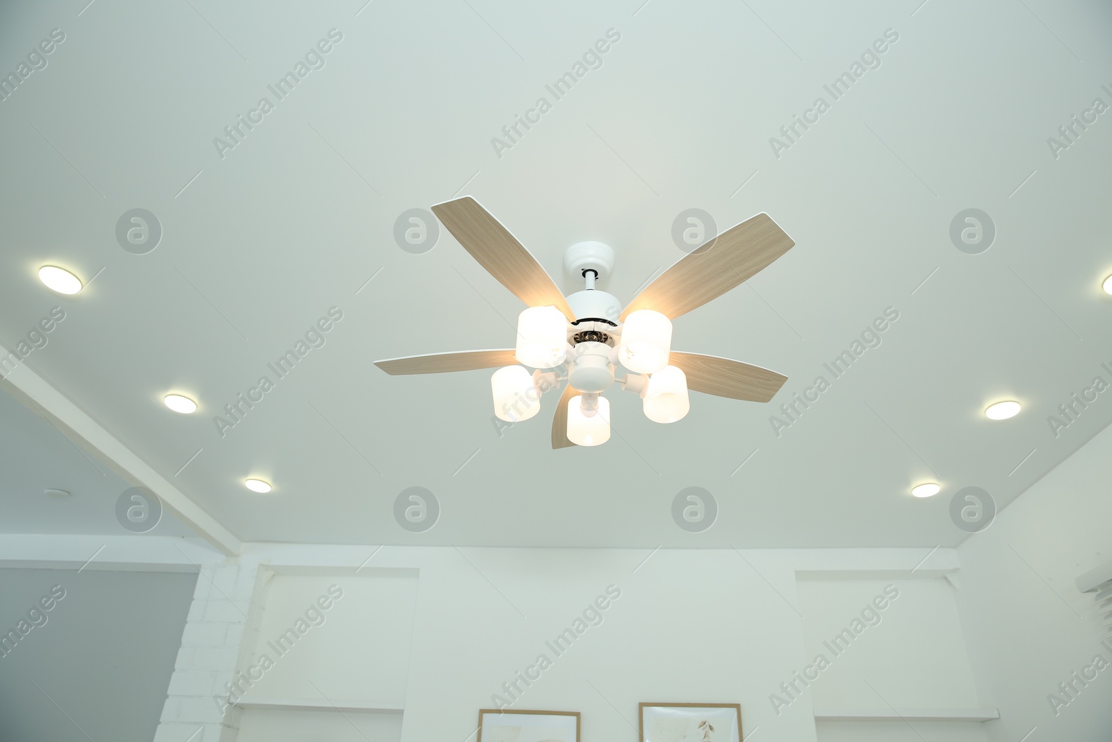 Photo of Ceiling fan with lamps indoors, low angle view