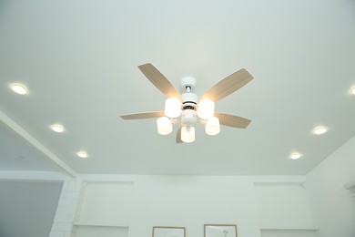 Photo of Ceiling fan with lamps indoors, low angle view