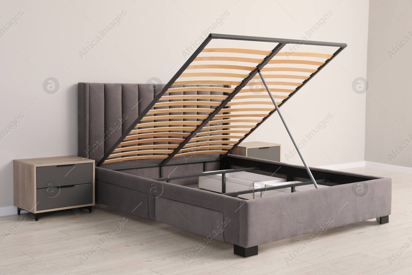 Photo of Comfortable bed with storage space for bedding under lifted slatted base in room